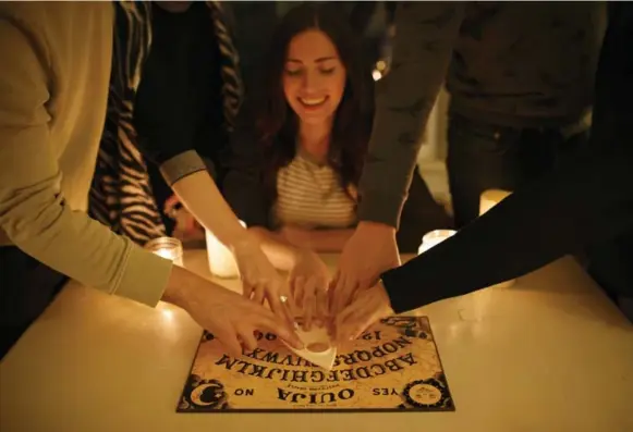  ?? COLE BURSTON/TORONTO STAR ?? Toronto Star reporter Lauren Pelley uses a Ouija board with friends on a dark and stormy Oct. 25.