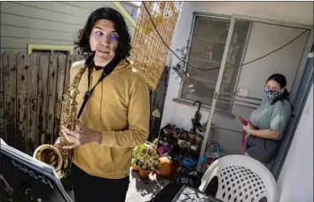  ?? Photograph­s by Brian van der Brug Los Angeles Times ?? ALHAMBRA HIGH SCHOOL senior Julio Illingwort­h pauses his saxophone practice on the front porch of his home as his sister exits to walk her dog. He has used the pandemic to spend more time learning music.