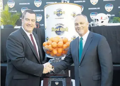  ?? WILFREDO LEE/AP ?? Wisconsin head coach Paul Chryst, left, and Miami head coach Mark Richt began the hype for the Orange Bowl by posing together during a press conference Wednesday in Hollywood.