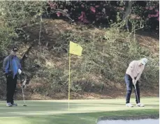  ?? ?? ↑ Bob Macintyre putts as Sandy Lyle watches in Augusta