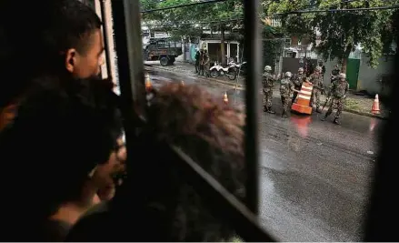  ?? Danilo Verpa/Folhapress ?? Moradores observam ação de soldados do Exército em bloqueios montados no bairro de Anchieta, na zona norte do Rio