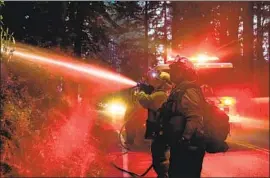  ??  ?? BARSTOW-BASED FIREFIGHTE­RS put down hot spots in Boulder Creek on Sunday. Volunteer firefighte­rs in the town have battled flames for days.