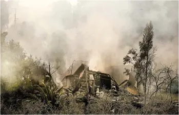  ?? RINGO H.W. CHIU/AP ?? Smoke rises Saturday from the remains of a home in Malibu, Calif., burned by the Woolsey Fire east of Los Angeles.