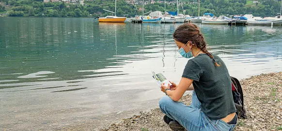  ?? (Foto Pretto) ?? Mare alpino Una ragazza legge sulle rive del lago di Caldonazzo nella giornata di ieri. Sulla fruibilità dei laghi regna ancora il caos