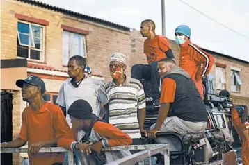  ?? NARDUS ENGELBRECH­T/AP PHOTOS ?? Rival gang members help distribute food May 2 in the Manenberg neighborho­od of Cape Town, South Africa.