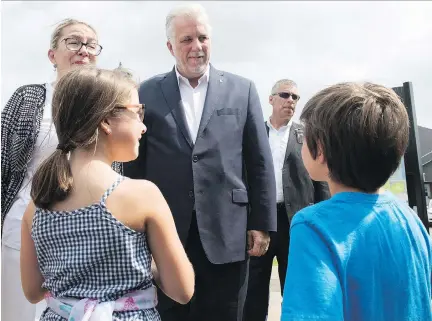  ?? JACQUES BOISSINOT/THE CANADIAN PRESS ?? Liberal Leader Philippe Couillard, accompanie­d by his wife Suzanne Pilot, speaks to youngsters as he arrives at a college Tuesday in St-Agapit. Couillard blasted CAQ Leader François Legault over proposed restrictio­ns on immigratio­n levels.