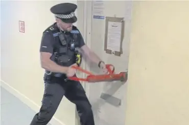  ?? ?? A police officer breaking the door of a flat in South Street, Gosport, where suspected Class C drugs were seized