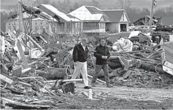  ?? ALEX BRANDON/AP PHOTOS ?? Mike Herrick, a member of the Putnam County Rescue Squad, leads President Trump on a tour Friday in hard-hit Cookeville, Tennessee. The storms killed 24 people in the state.