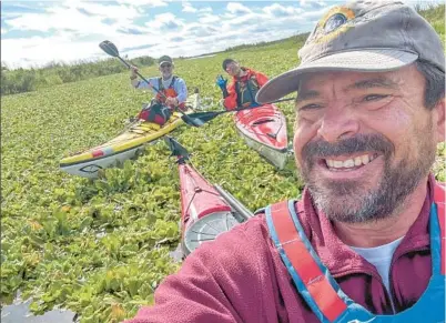  ?? GREG PFLUG ?? DAY 1: Greg Pflug takes a selfie with Patrick Connolly, center, and Fred Goebel in the background in a canal clogged with water hyacinth on the St. Johns River on Dec. 29.