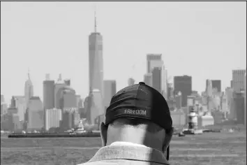  ?? BEBETO MATTHEWS / AP ?? Eddie Bracken wears a cap with the word “freedom” while preparing Sept. 2 for an interview at the Staten Island September 11th Memorial, in view of lower Manhattan in New York. Bracken, a carpenter whose sister Lucy Fishman was killed in the Sept. 11 attacks on the World Trade Center, is awaiting the trial of the attack’s self-professed architect, Khalid Sheik Mohammed, and his co-defendants at Guantanamo Bay, Cuba.