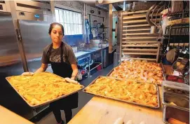  ?? MARK HUMPHREY/ASSOCIATED PRESS ?? Sandra Castillo removes pretzels from the oven at Von Elrod’s Beer Hall And Kitchen on Tuesday in Nashville, Tenn. For the restaurant, located across the street from Nashville’s minor league baseball stadium, which sees big crowds in the summer, both inflation and the worker shortage have sent costs skyrocketi­ng.