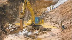  ?? JERRY JACKSON/BALTIMORE SUN ?? An excavator breaks up rock on the site of the installati­on of a pair of undergroun­d water tanks at Druid Lake. The site eventually will become 14 new acres of parkland.