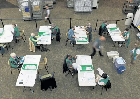  ?? Hyoung Chang, The Denver Post ?? Election judges check ballots Thursday in the main lobby of the Denver Elections Division to allow for physical distancing.