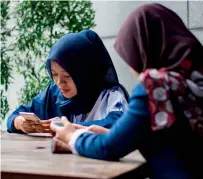  ?? AFP ?? Women use their smart phones at a cafe in Jakarta. —