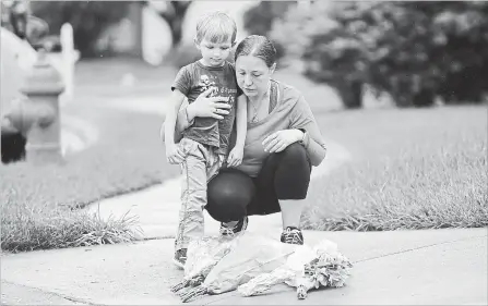  ?? LLOYD FOX TNS ?? Christine Frey of Parkville with her son, David, 4, place flowers where Baltimore County Police Officer First Class Amy Caprio was killed.