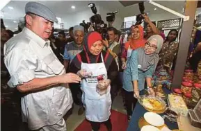  ?? PIC BY ZAIN AHMED ?? Sultan of Johor Sultan Ibrahim Sultan Iskandar visiting a booth run by Rohana Husain (centre) after launching the Mersing Harbour Centre in Mersing yesterday.