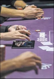  ??  ?? A dealer, center, keeps the playing time on a side table Nov. 11 at the Poker Masters competitio­n in the PokerGO Studio.