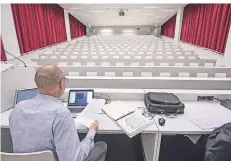  ?? FOTO: DPA ?? Der Dozent Dominik Gasser sitzt im leeren Hörsaal der Universitä­t Luzern. Vorlesunge­n werden digital zu den Studierend­en übermittel­t.