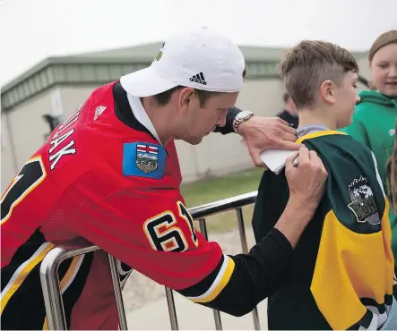 ?? PHOTOS: KAYLE NEIS /THE CANADIAN PRESS ?? Calgary Flames defenceman Brett Kulak signs a jersey for a fan outside Elgar Petersen Arena during the Humboldt Hockey Day event in Humboldt on Friday. Thousands of people turned out to take part in activities, meet NHL players and see the Stanley Cup.