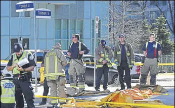  ?? REUTERS ?? Fire fighters stand near a covered body at a major intersecti­on in Toronto on Monday.