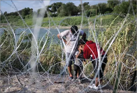  ?? PHOTO BY ANDREW CABALLERO-REYNOLDS/AFP VIA GETTY IMAGES ?? Victor Ferreira, from Venezuela, looks on as his wife Alexandra Espinosa kisses their son Tiago, 4, while waiting to cross razor wire into Eagle Pass, Texas, Monday.