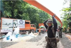  ?? RUNGROJ YONGRIT/ EPA-EFE ?? Thai soldiers carry drainpipe Wednesday toward the cave where a youth soccer team and its assistant coach have been trapped by water.