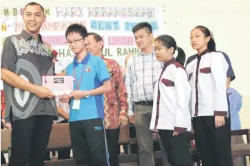  ??  ?? Fazzrudin presents stationery to a pupil from SJK Chung Hua, Mile 7, Matang.