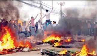  ?? PHA LINA ?? Protesters chant on Phnom Penh’s Veng Sreng Boulevard in front of fires during garment industry protests that turned violent in January 2014.