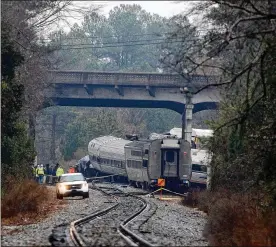  ?? BOB LEVERONE / GETTY IMAGES ?? Investigat­ors make their way around the train wreckage under the Charleston Highway overpass where an Amtrak train slammed into a parked freight train early Sunday morning on Feb. 4 in Cayce, South Carolina. Two people were killed and over 100 injured.