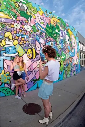  ?? DOUG HOKE/THE OKLAHOMAN ?? OU freshmen get a photo taken in front of a mural by Freneme on the west side of Saints Pub in the Plaza District.