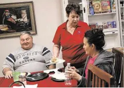  ?? Elizabeth Conley / Houston Chronicle ?? Debra McCammon, director of Huntsville’s Hospitalit­y House, gives cake to Don and Brianna Bonneville, who visited their incarcerat­ed son on Oct. 30.