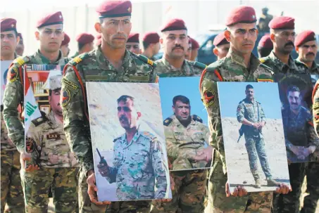  ?? Ahmad Al-rubaye / AFP / Getty Images ?? Members of the Rapid Response military unit hold portraits of fallen soldiers at a ceremony at Baghdad Internatio­nal Airport.