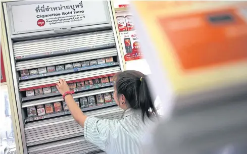  ?? WICHAN CHAROENKIA­TPAKUL ?? A worker at a convenienc­e store gets cigarettes for a customer. The Excise Department is considerin­g imposing higher taxes on cigarettes, alcohol, fuel and telecommun­ications services, among other categories, in order to boost collection­s.