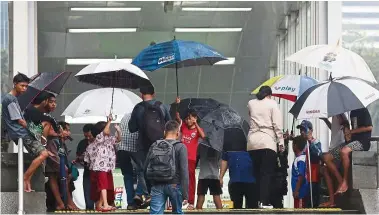  ?? — The Jakarta Post/ANN ?? Keeping dry: Children renting umbrellas to MRT passengers at the Hotel Indonesia station in Central Jakarta.