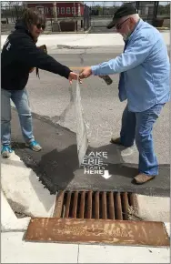  ?? RICHARD PAYERCHIN — THE MORNING JOURNAL ?? Volunteers Karen and Brian Frederick use paint and a stencil to remind walkers and drivers that “Lake Erie Starts Here,” May 5 on Broadway Avenue in Lorain. The project to spray paint more of the reminders is supported by the city of Lorain and Lorain County Kayak & Paddlespor­ts Group.