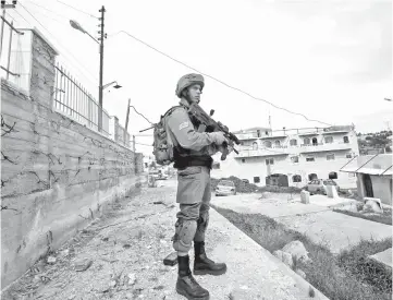  ??  ?? An Israeli soldier stands guard at the scene of an attempted stabbing attack in Hebron, in the occupied West Bank. — Reuters photo