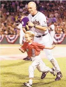  ?? STEPHEN JAFFE/GETTY ?? Orioles third baseman Cal Ripken Jr. chases after his son Ryan as they run to the dugout at the All-Star Game in July 1999.