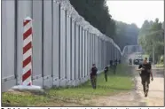  ?? (AP/Michal Dyjuk) ?? Polish border guards patrol a newly built metal wall on the border between Poland and Belarus, near Kuznice, Poland on Thursday.