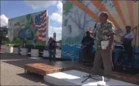  ?? JORDANA JOY — THE MORNING JOURNAL ?? Executive Director Antonio Barrios, left, of Lorain Arts Council speaks after the unveiling of a mural painted by veterans behind the building at 737 Broadway Ave. in Lorain. The mural is visible from Black River Lane.