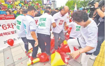  ??  ?? South Korean conservati­ve activists burst balloons with yellow banners reading ‘ICBM’ and ‘SLBM’ – the respective acronyms for interconti­nental ballistic missile and submarine-launched ballistic missile – and ‘North Korea Nuclear Weapons’ during a...