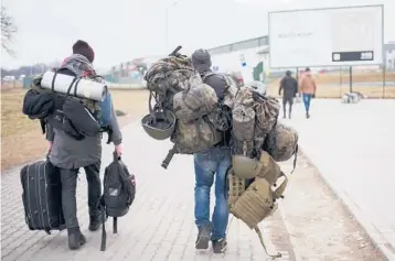  ?? MARKUS SCHREIBER/AP ?? A man carries combat gear as he leaves the border crossing in Medyka, Poland, to fight in Ukraine.