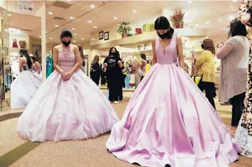  ?? JOHN J. KIM/CHICAGO TRIBUNE ?? Twin sisters Josefina and Dania Herrera, 14, look down at their final choices on quinceañer­a dresses at Peaches Boutique on Feb. 27 in Chicago. Both girls decided on lavender-colored dresses.