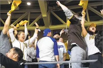  ?? Meg McLaughlin San Diego Union-Tribune ?? PADRES FANS live it up at the expense of two dejected Dodgers followers following San Diego’s Game 3 win in the NL Division Series at Petco Park. The Padres blocked anyone from L.A. County from buying tickets.