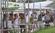  ??  ?? Asylum seekers look at the media from behind a fence at the Manus Island Detention Centre, Papua New Guinea.