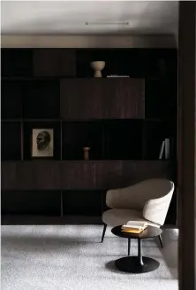  ??  ?? This page, bottom
The dark joinery is softened by a Henrik Pedersen-designed Charlotte armchair from BoConcept and Bloop coffee table by Regular Company for Artisan
Facing page
The monochroma­tic scheme continues in the master bedroom, where the custom upholstere­d headboard in Romo’s Linara Chinchilla is paired with a Bordeaux bedside table by Morten Georgsen for BoConcept, and a collection of dark vessels