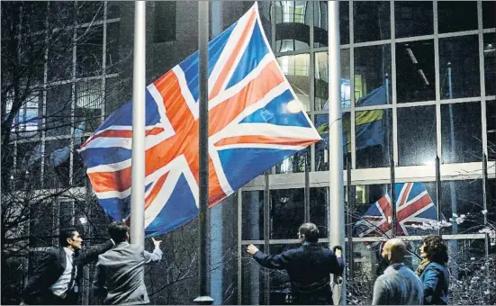  ?? TOLGA AKMEN / AFP ?? Empleats del Parlament Europeu arrien la bandera britànica de l’edifici legislatiu a Brussel·les