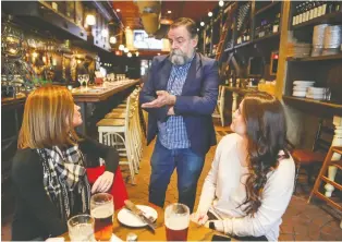  ?? JOHN MAHONEY ?? Roger Costa, partner and general manager at Wienstein and Gavino’s in downtown Montreal, speaks to customers Colleen Wolfe, left, and Taryn Eilers. “The instinct is to accommodat­e the guest,” he says.