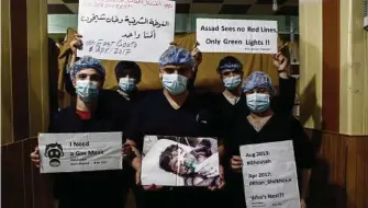  ??  ?? Medical staff at Damascus Countrysid­e Specialize­d Hospital hold placards condemning a suspected chemical weapons attack on the Syrian town of Khan Sheikhu in the rebel-held Idlib province during a gathering to show solidarity with the victims. Sameer...