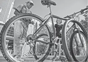  ?? PHOTOS BY CHRIS LANDSBERGE­R/THE OKLAHOMAN ?? Angela Atkins, First Baptist Church of Norman's director of community ministry, helps Kevin Moore with his new bike he picked out during the church's monthly Bikes and Bibles giveaway.