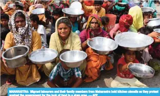  ?? — AFP ?? MAHARASTRA: Migrant labourers and their family members from Maharastra hold kitchen utensils as they protest against the government for the lack of food in a slum area.